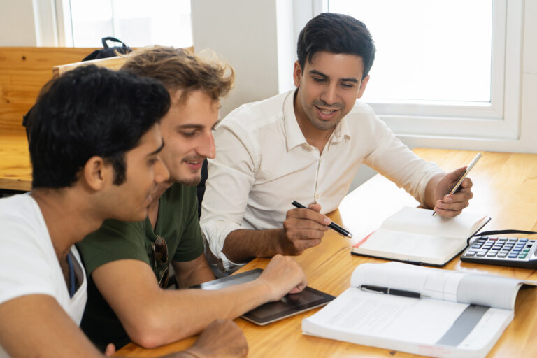 Young teacher telling two students about corporate budgeting. Two young guys in casual tshirts listening to confident man in white shirt. Business school concept